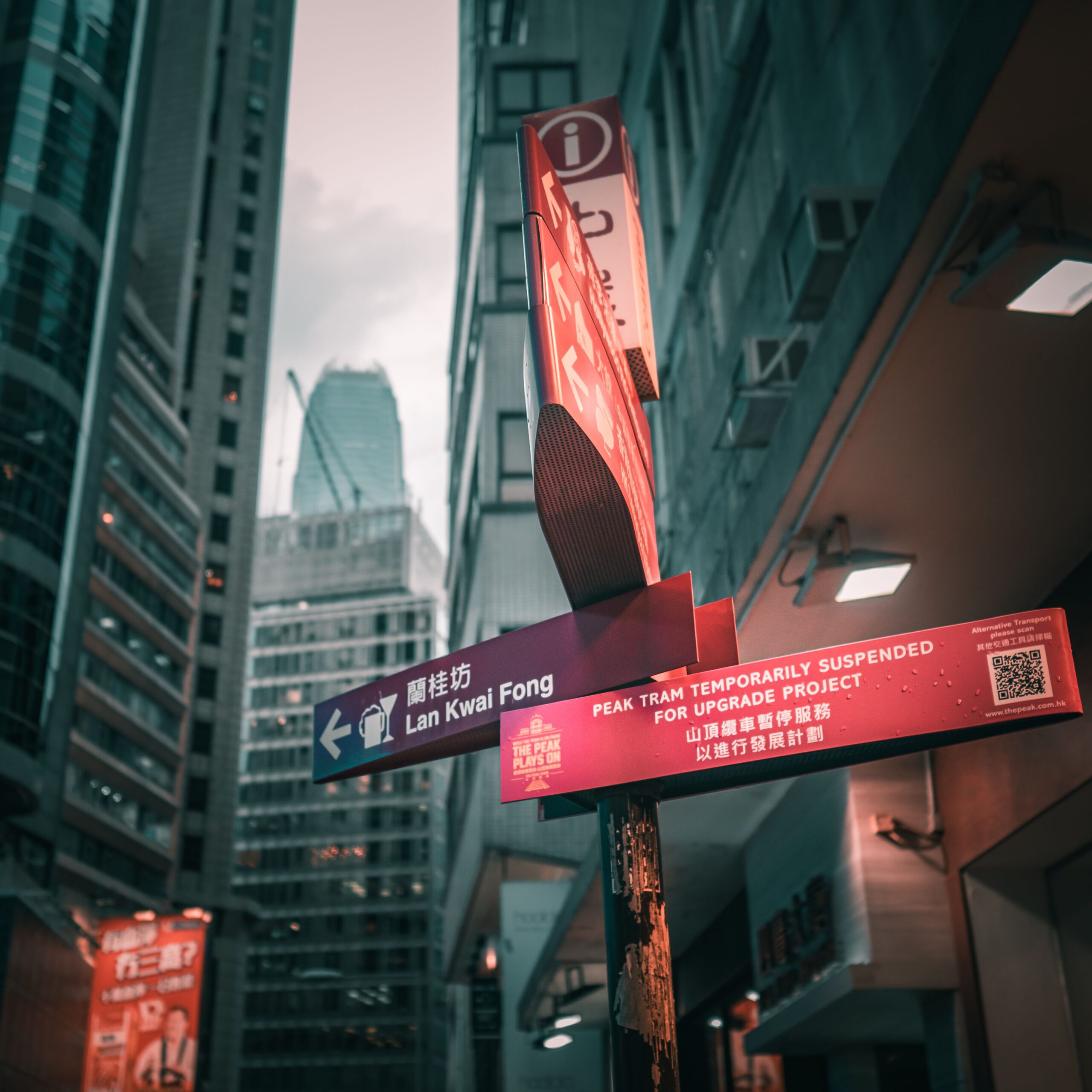 From below of direction signboard placed on street of Hong Kong with modern skyscrapers